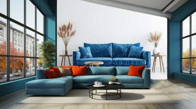 A blue velvet sofa with wooden legs and two side tables with vases and plants in a modern living room Wall mural