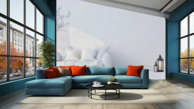 A minimalist living room with a white sofa. a branch. and two black lanterns The wall is white with a soft light coming in from the left Wall mural