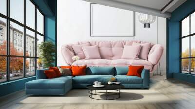 A pink sofa with pillows and a coffee table in front of a blank picture frame on a white wall, with a modern floor lamp hanging over the couch Wall mural