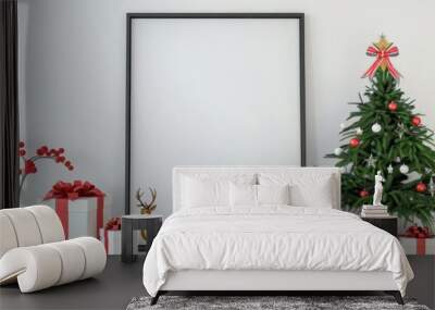 Mockup of a blank frame with Christmas decor. A large black frame with a white background sits next to a decorated Christmas tree with red and white ornaments and a gold deer. wrapped present Wall mural