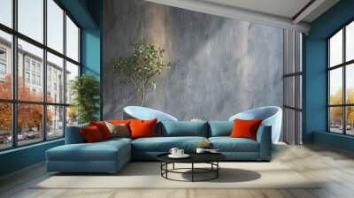 Two blue armchairs with a round table in front of a grey wall with a potted plant in the corner Wall mural