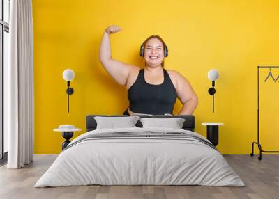 Hispanic overweight fitness model wearing sportswear in strong and fearless pose raising arm. Body Positive And Sport As Lifestyle. Showing muscules Wall mural