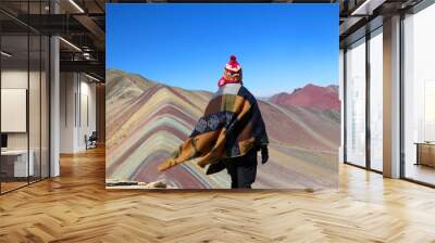 Rainbow mountain or seven colors mountain view in the red valley in the andes. Poncho and chullo are the two main dressing peruvian clothes in the picture. Wall mural