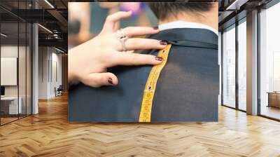 Detail of tailor's hands taking measurements for a man dress Wall mural