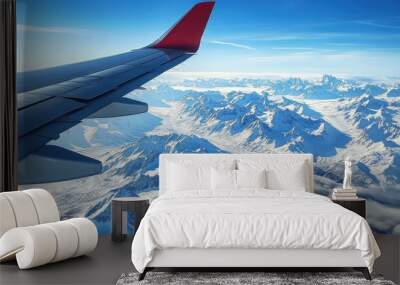 airplane wing in flight, with snow-capped mountains below Wall mural