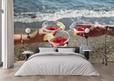 Three women with red coctails at a beach party Wall mural