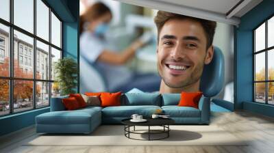 A smiling man sitting in a dental chair while a dentist examines his teeth Wall mural