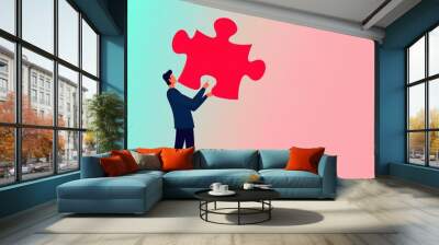 A businessman is holding a large red puzzle piece, symbolizing the search for solutions and creativity in the workplace. The modern design emphasizes teamwork and innovation. Wall mural