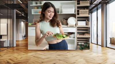 Happy Asia woman eating salad in kitchen room Wall mural