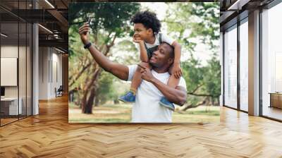 happy black people father and son riding on the father back selfie in the park Wall mural