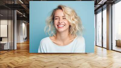 Portrait of a beautiful young woman with blond hair on blue background Wall mural