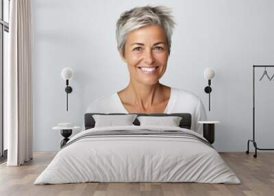 Portrait of smiling senior woman with short grey hair against white background Wall mural