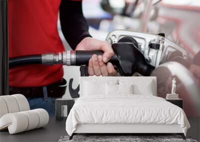 Gas station worker in red uniform filling up bronze pickup truck tank. Closeup hand holding black gas pump nozzle. Wall mural