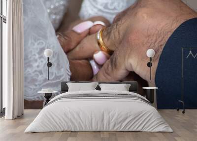 The bride places the gold wedding ring on the hand of the groom during the ring exchange Wall mural