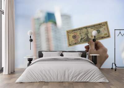 Hand holding banknote dollar and showing money. There is a building background. Wall mural