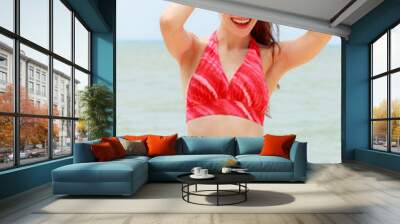 Beautiful women in red bikini pose behind the sea. Wall mural