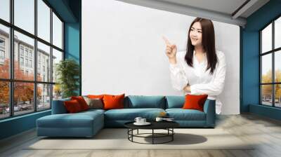 Beautiful asian woman pointing to copy space. Wall mural