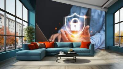 The technology of security for protect private data of personal. Technology, business, and innovation concept. Businessman holding a lock with a shield on hand to safeguard violation of privacy. Wall mural