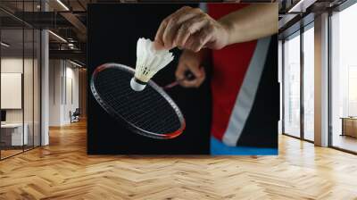 A badminton player postures the face of the racket to serve the badminton ball in the match Wall mural