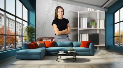 young caucasian woman sit on sofa and looks at camera with book and shelf background. pretty caucasian woman relax working business at home office Wall mural