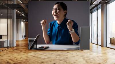 Asian woman happy in blue shirt make winning gesture working on a laptop at office. isolated on white background. Wall mural