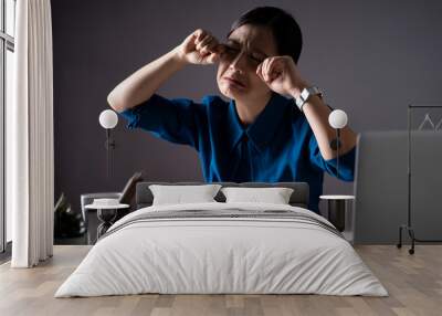 Asian woman in blue shirt sad and crying, working on a laptop at office. isolated on background. Wall mural