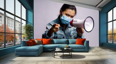 Asian woman wearing protective face mask shouting with megaphone isolated over white background. Wall mural