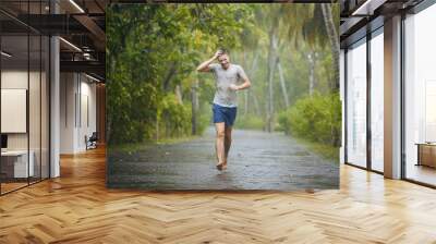 drenched young man runing on road in heavy rain.. Wall mural