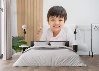 Happy savings. Asian little cute boy with a piggy bank on home. The child smiles happily and hugs him tightly and shows him a thumbs up. The concept of saving money for a dream. Wall mural