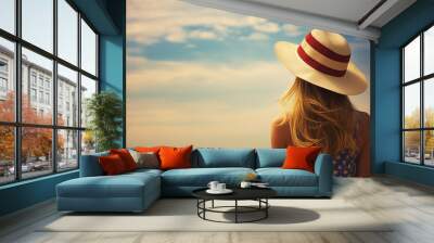 woman wearing a hat stand on beach in summer light Wall mural