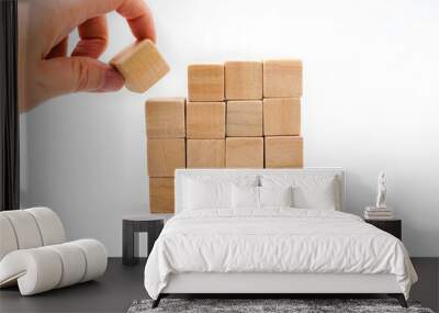 hand pick a wooden cube from stack on white background Wall mural