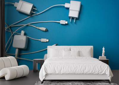 Top view or flat lay of White mobile power charger and USB in multiple types laid disorderly and mess on blue pvc sheet texture background , energy management concept ,with copy space Wall mural