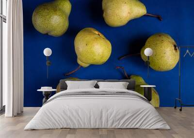 Over ripe green delicious pear against blue background. Zero waste and organic food concept
 Wall mural