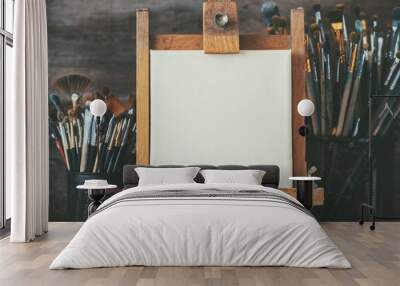 Artistic equipment in a artist studio: empty artist canvas on wooden easel and paint brushes Retro toned photo. Wall mural