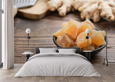 Bowl of candied ginger pieces and ginger roots on wooden kitchen table. Wall mural