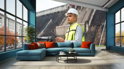 Professional asian maintenance engineer man with safety helmet in construction site dam with hydroelectric power plant and irrigation. Manager engineer man working at project big building. Wall mural