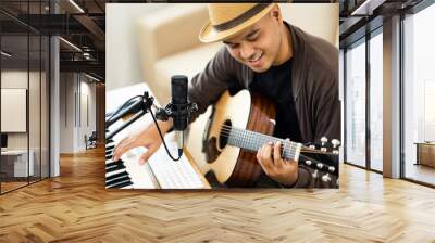 Professional Musician with condenser microphone and tablet for Mixing Mastering music. Hispanic male composing a song with guitar and piano keyboard at digital Recording home studio Wall mural