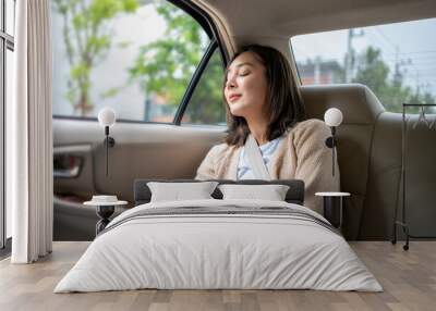 Relaxing moment of beautiful woman sleeping in car back seats with safety belt. Female happy in car while traveling on the road to your destination.a Wall mural