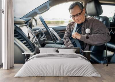 Senior asian men getting new car and putting on his seat belt before driving car. Safety drive concept. Wall mural