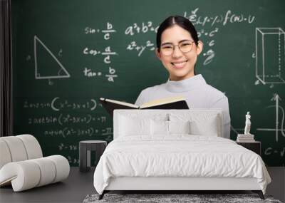 Young asian teacher woman teaching holding book and video conference with student looking camera. Female teacher training the mathematics in classroom blackboard from online course. Wall mural