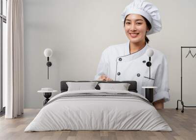 Young beautiful asian woman chef in uniform holding soup pot ladle utensils cooking in the kitchen various gesture menu good taste on isolated. Cooking woman chef people in kitchen restaurant Wall mural