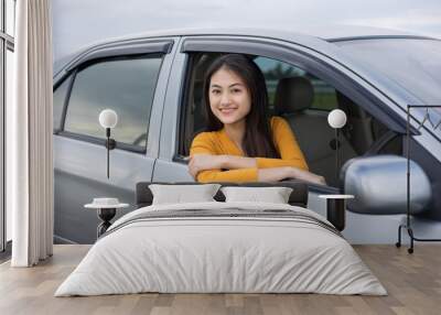 Young beautiful asian women getting new car. she very happy and excited. she sit and touching every detail of car. Smiling female driving vehicle on the road Wall mural