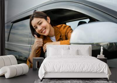 Young beautiful asian women getting new car. she very happy and excited. Smiling female driving vehicle on the road on a bright day. Sticking her head outta the windshield Wall mural