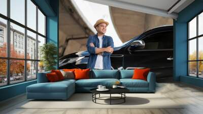 Young handsome asian man getting the new car.He standing with arm crossed in front of the car.He very happy. Buy or rent a car concept. Wall mural