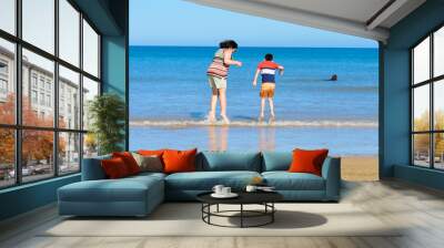 mother and son jumping in the sea water near beach in summer Wall mural