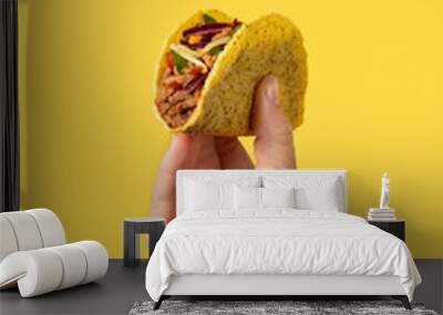 Hand holding a Mexican taco beef on yellow background Wall mural