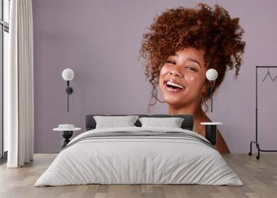 Curly hair for the win. Studio shot of a beautiful young woman posing against a pink background. Wall mural