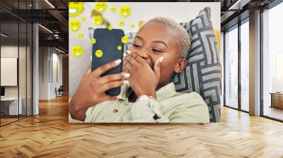 Black woman on sofa with phone, laughing and emoji on social media, message or video online. Happy face, smile and internet, girl on couch with digital app on smartphone and funny viral meme in home. Wall mural