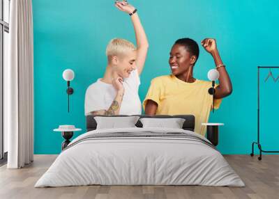 Grab your girl and get grooving. Studio shot of two young women dancing together against a turquoise background. Wall mural