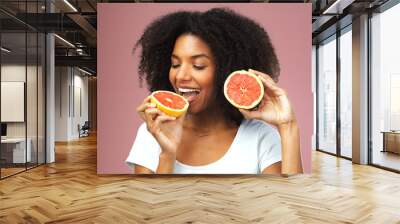 Grapefruit, happy and black woman eat in studio isolated on a pink background. Natural, fruit and African female model eating food for vegan nutrition, vitamin c or healthy diet, hungry and wellness. Wall mural